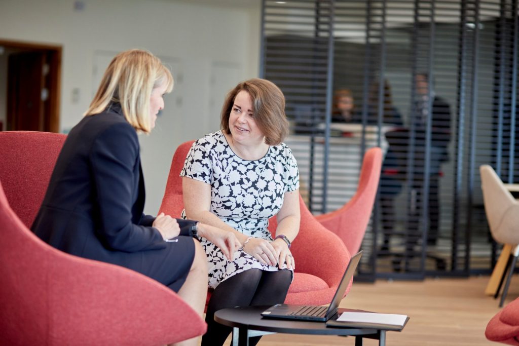 Two women, sitting down talking in an office