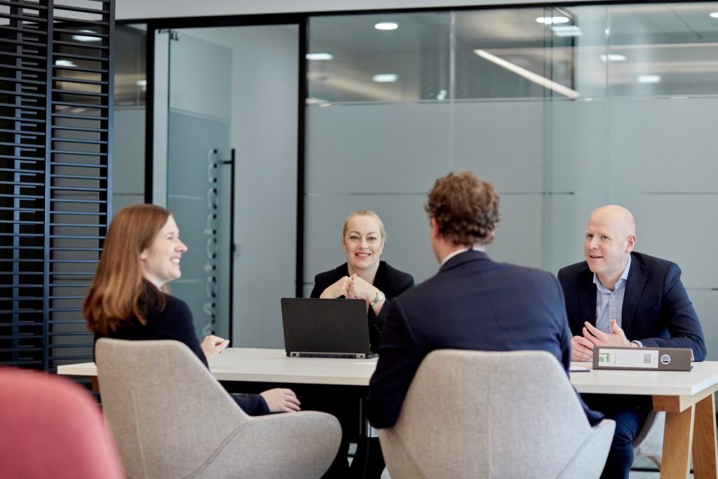 A group of people talking around an office table.