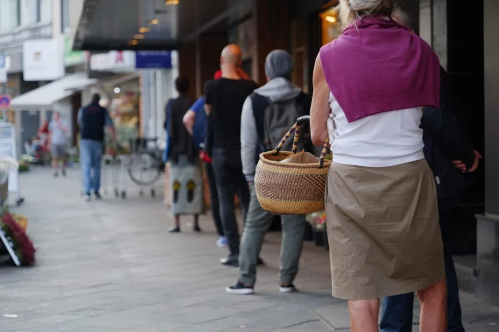 A queue of people outside a shop observing social distancing